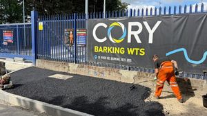 Operative laying asphalt within new kerb lines outside Cory's Barking Transfer Station on River Road, Barking