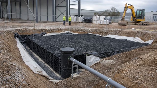 Surface water attenuation crates and drainage pipe within a protected excavation at a UK warehouse construction site